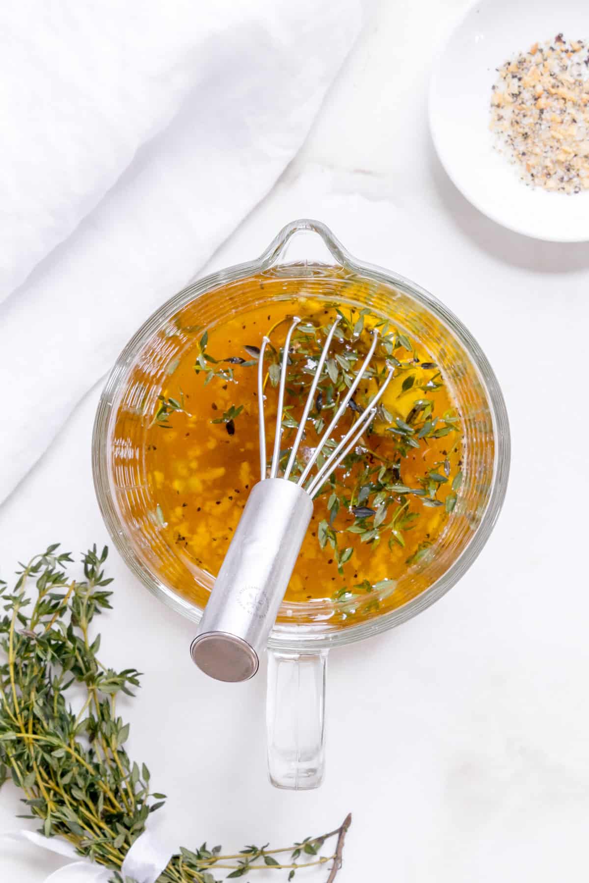 ingredients for apple cider vinaigrette in a glass measuring up with a whisk.