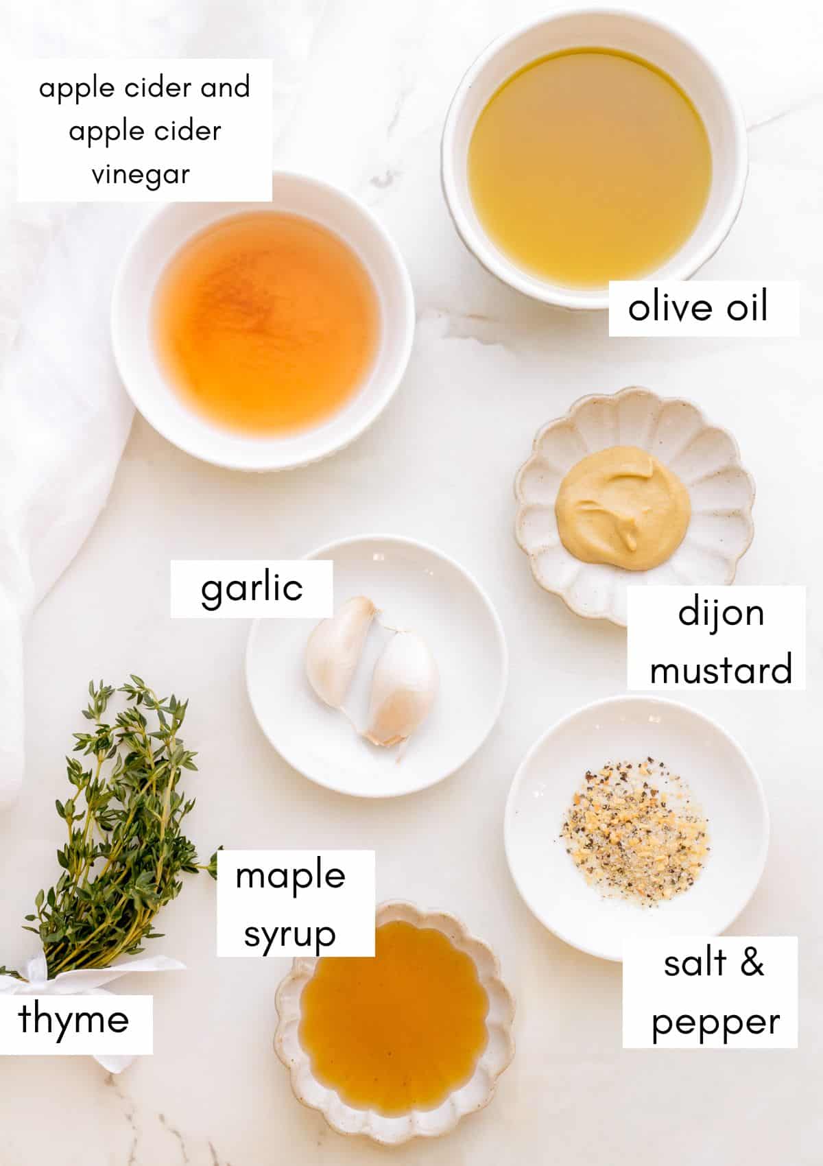 labeled ingredients for apple cider vinaigrette on white counter.