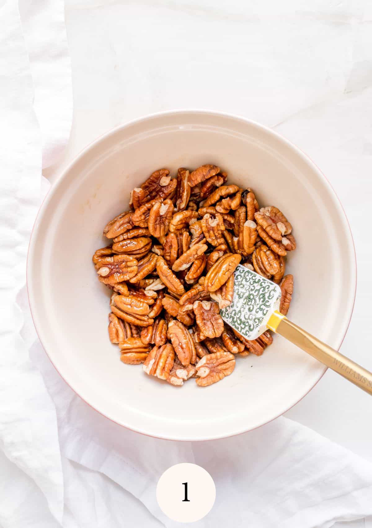 pecans, maple syrup and seasoning in a small mixing bowl on marble background.