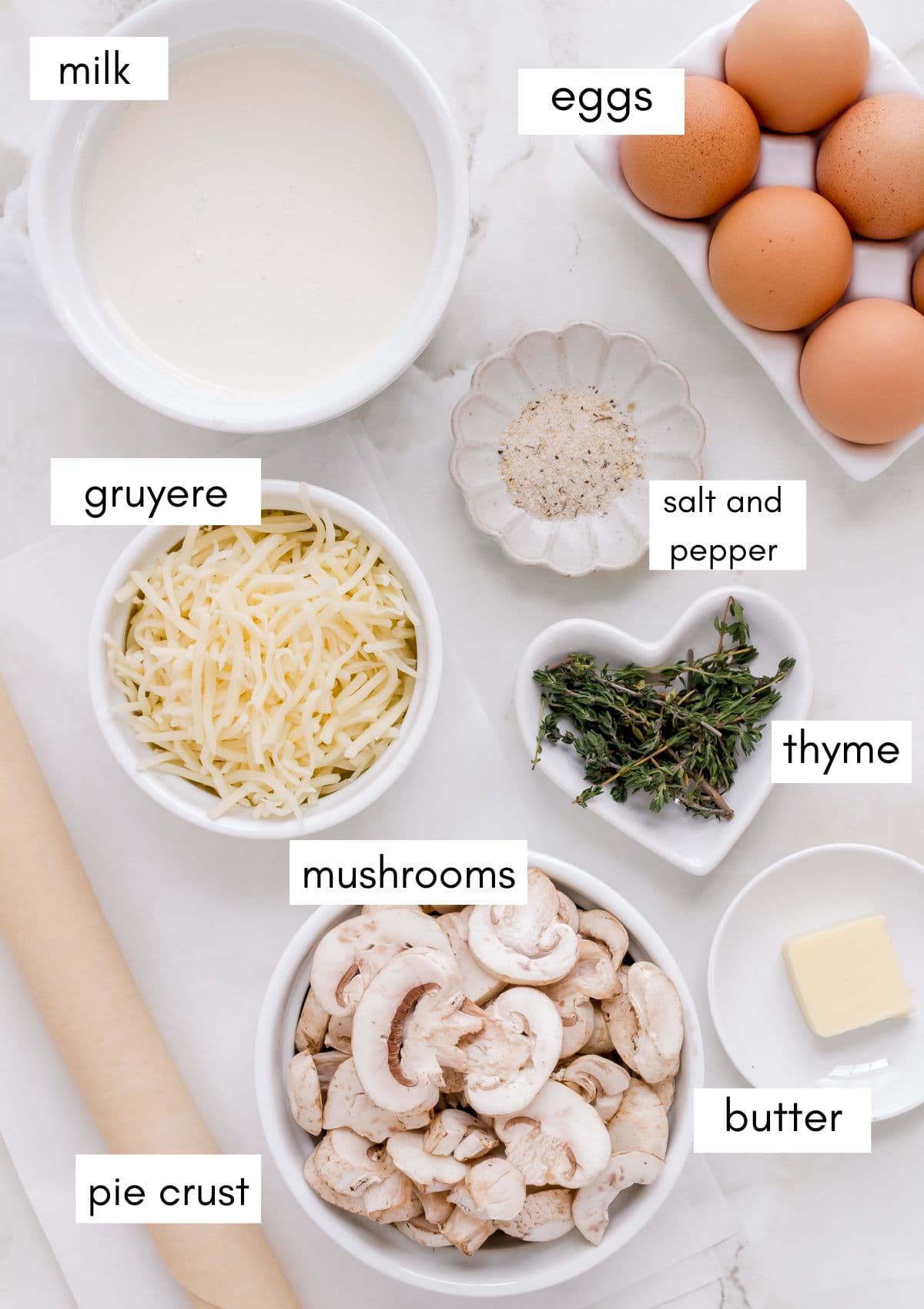 labeled ingredients for mushroom quiche on marble background.