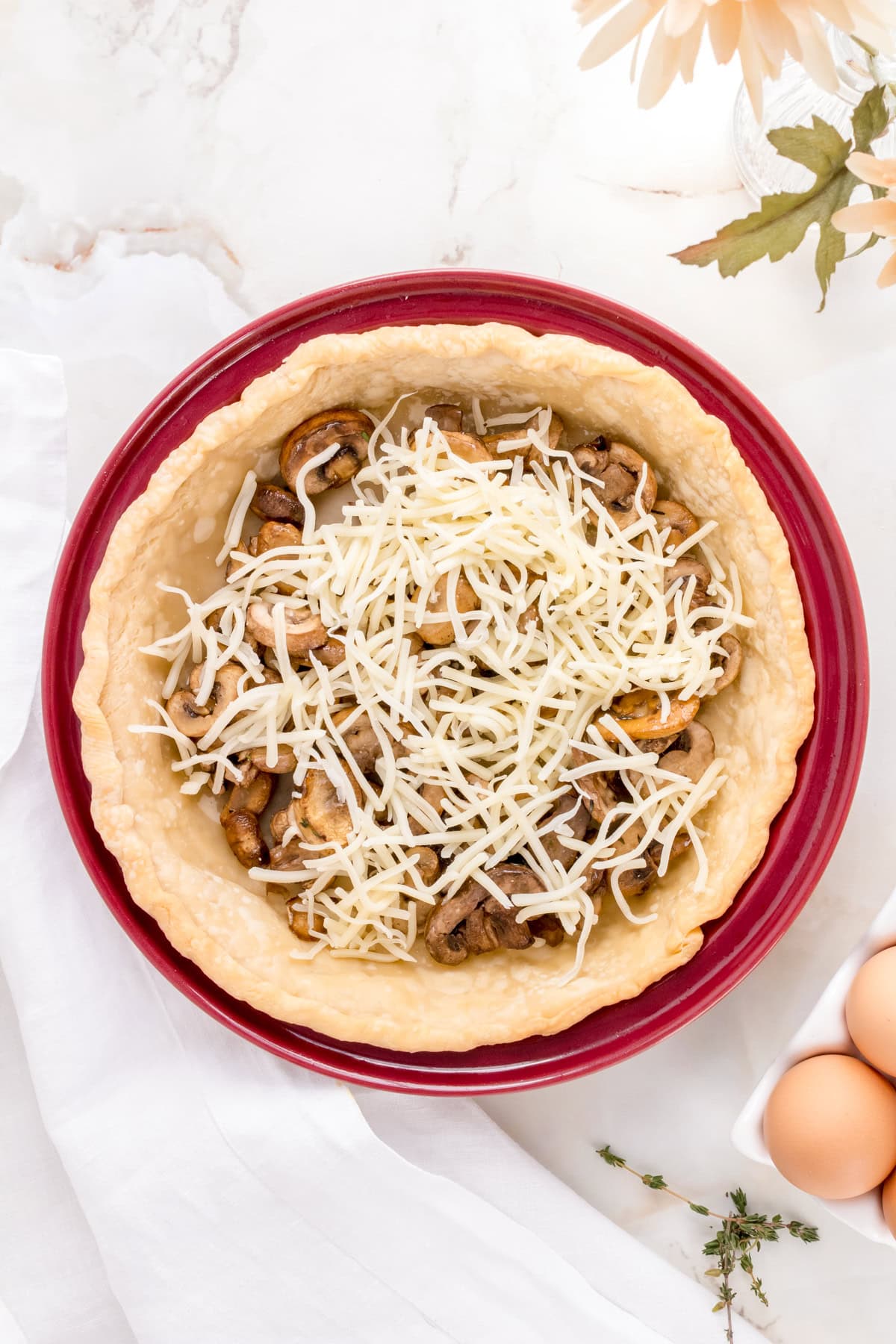 mushrooms and gruyere in pie crust with eggs on marble background.