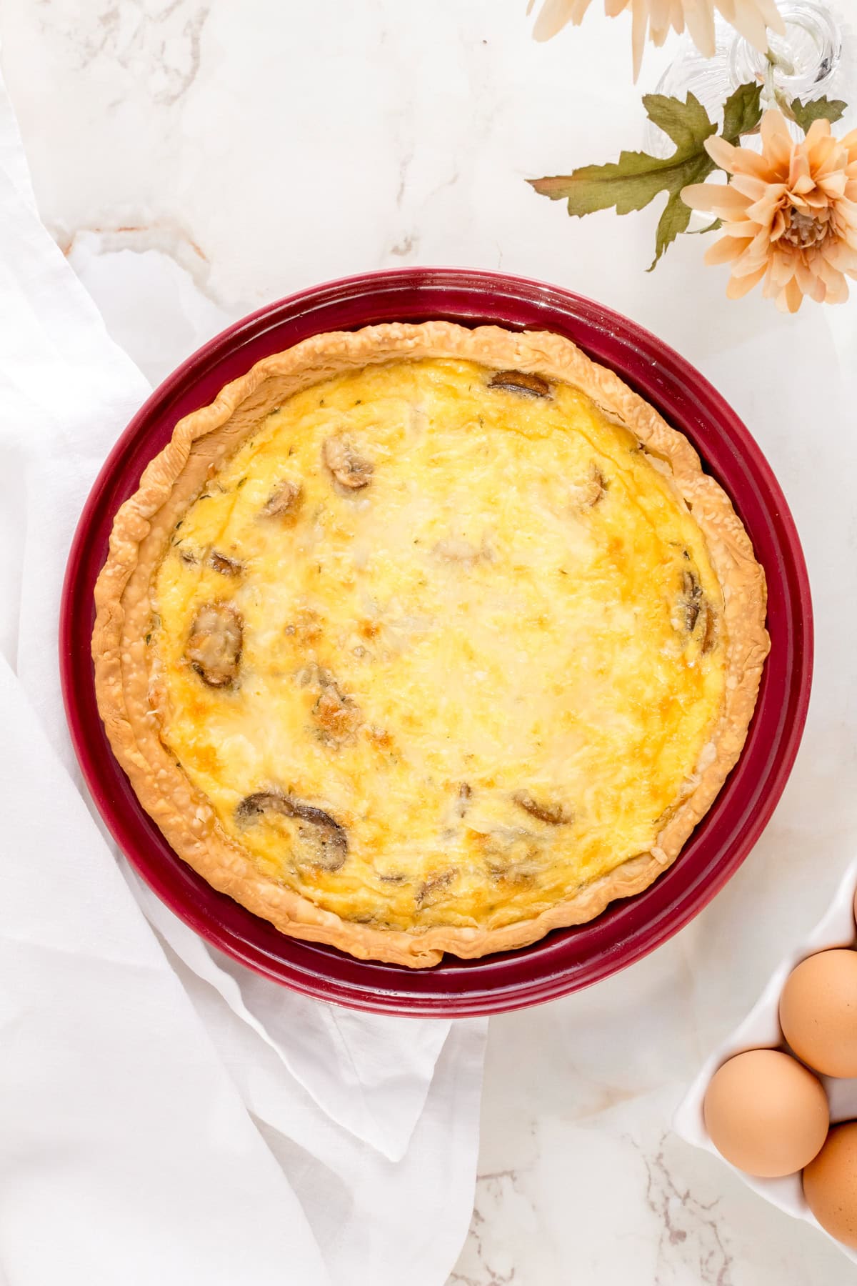 mushroom gruyere quiche ready to serve in red pie dish.