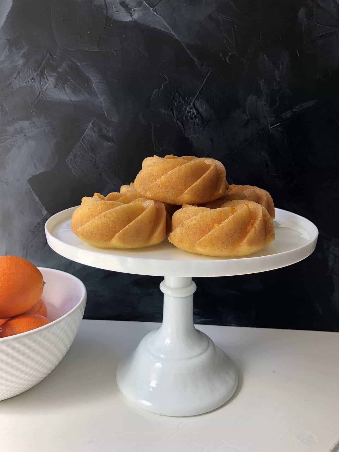 https://mapleandthyme.com/wp-content/uploads/2018/04/Orange-Bundtlette-Cakes-on-Cake-Stand-with-Bowl-of-Oranges.jpg