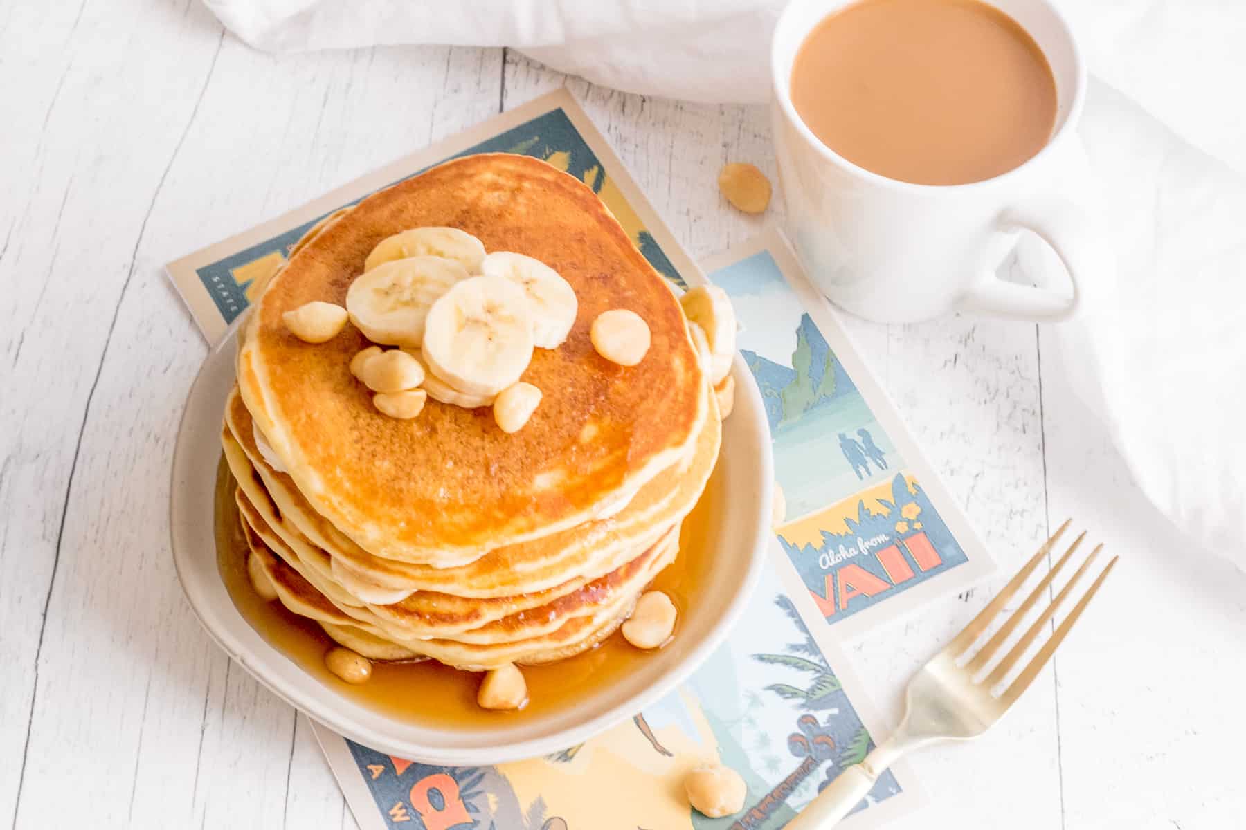 stack of banana macadamia nut pancakes with coffee and fork.