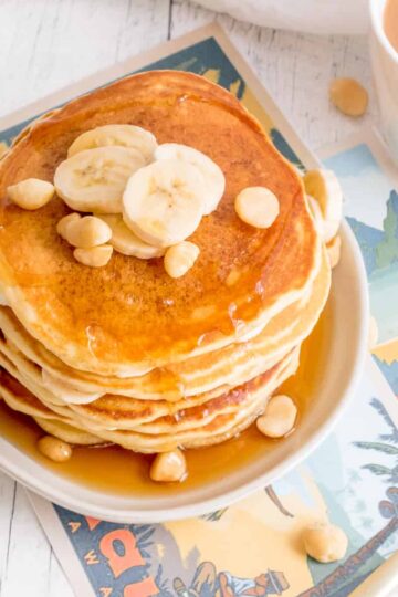 banana macadamia nut pancakes on plate with coffee.