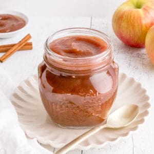 crock pot apple butter with spoon, apple and cinnamon.