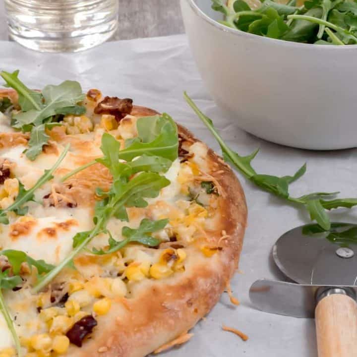sweet corn and bacon pizza with salad and glass of white wine