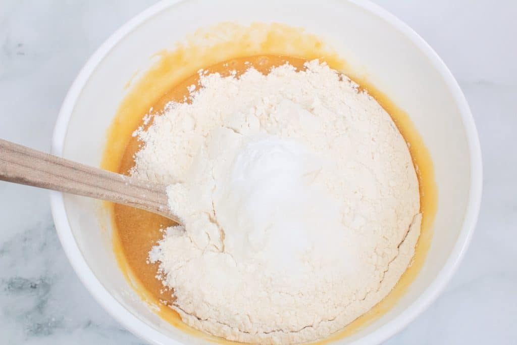 adding dry ingredients to s'mores cookie dough in white mixing bowl.
