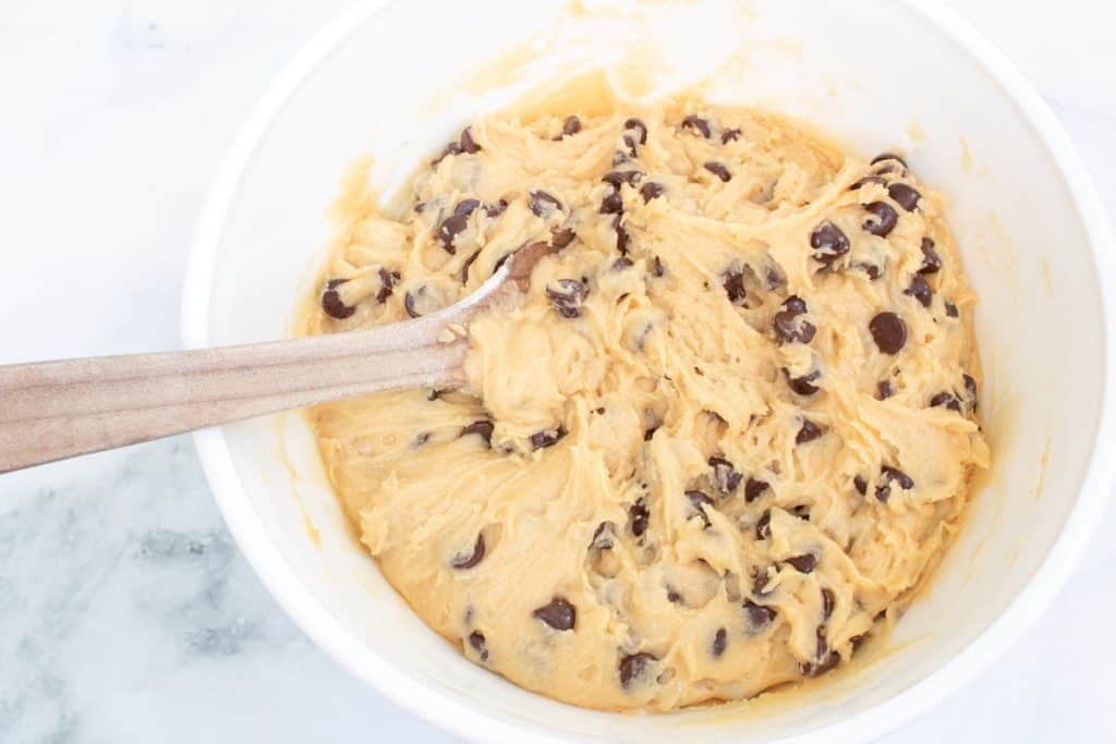 a white mixing bowl filled with dough for s'mores cookies.