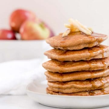 apple butter oatmeal pancakes on a plate with basket of apples