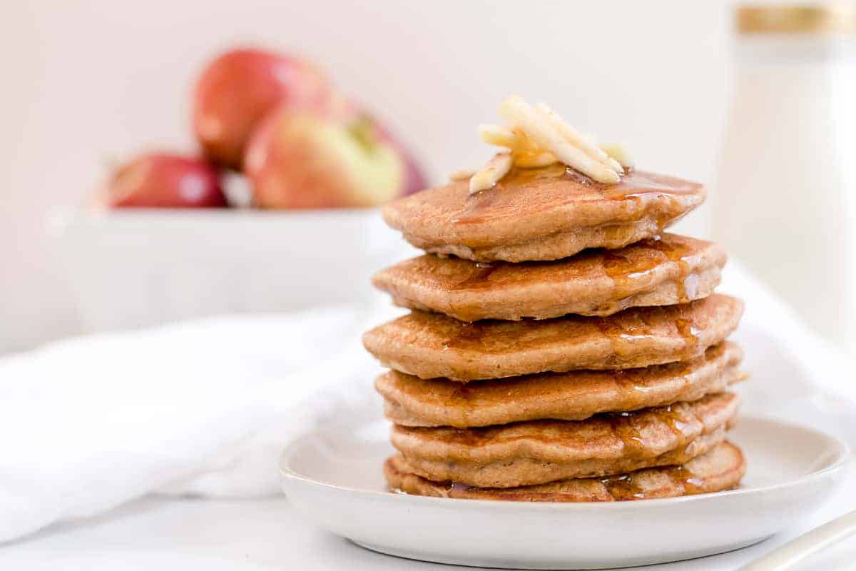 apple butter oatmeal pancakes on a plate with basket of apples