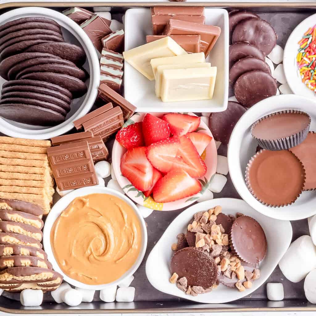 ingredients for s'mores dessert board on black tray.