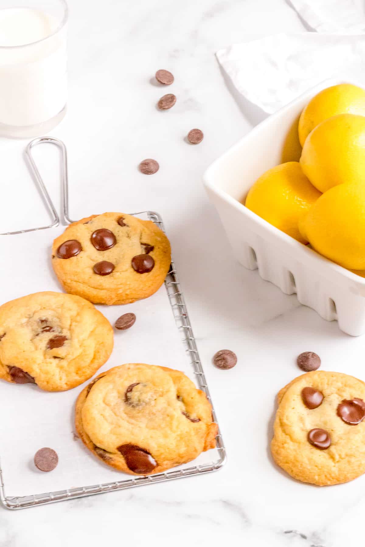lemon chocolate chip cookies on a cooling rack with a basket of lemons