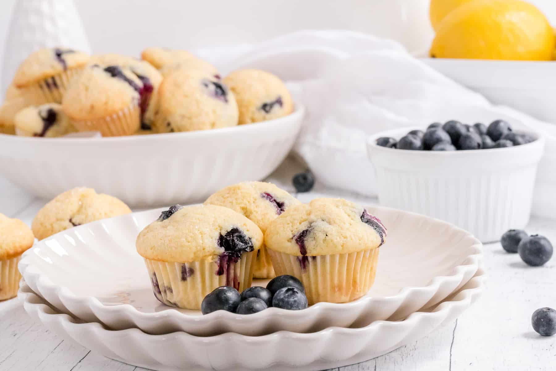 a bowl of mini blueberry muffins on a table with milk and berries