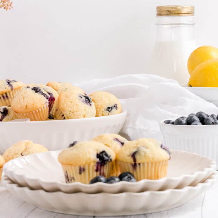 mini blueberry muffins on white plate with bottle of milk and basket of lemons
