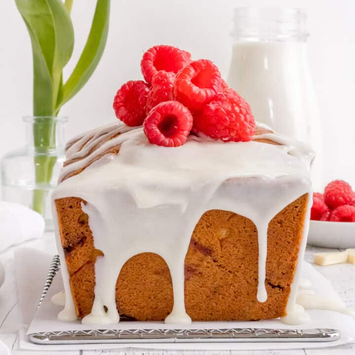 raspberry and white chocolate loaf cake on wire rack with milk bottle