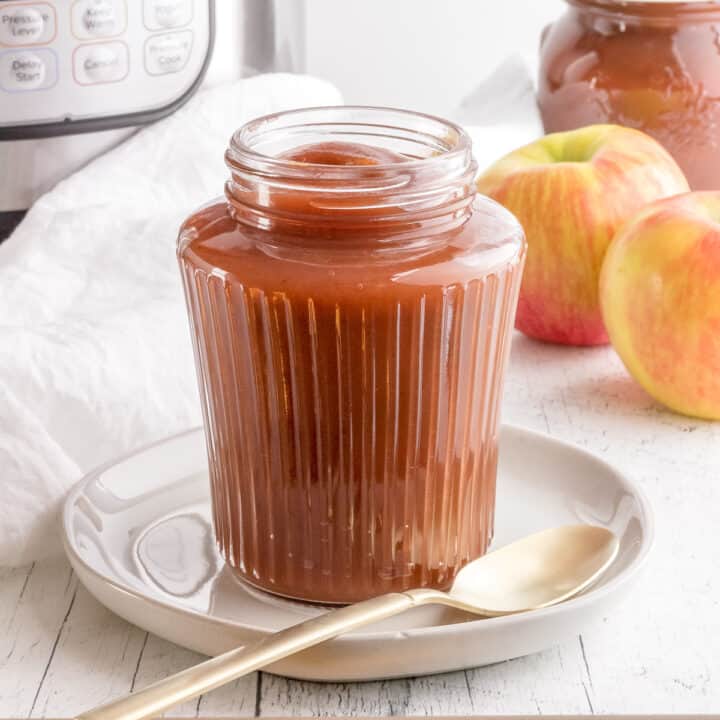 jar of homemade apple butter with Instant Pot and apples.