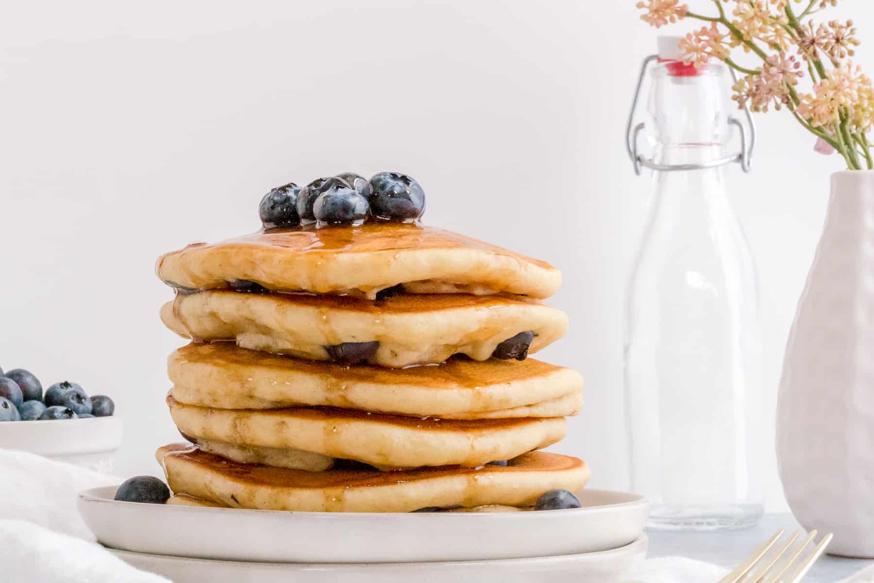 stack of gluten free blueberry pankcakes on white plate.