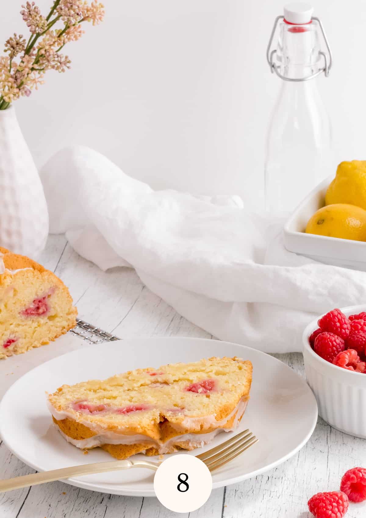 lemon raspberry loaf cake with bowl of raspberries and basket of lemons/