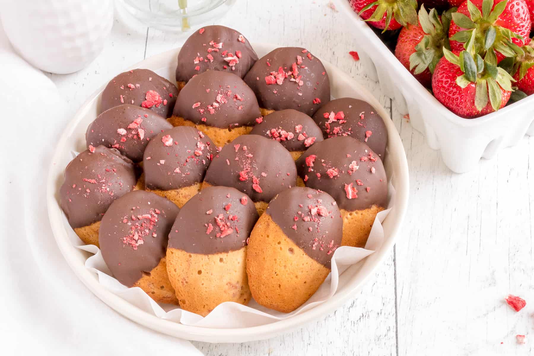 chocolate covered strawberry madeleines with a basket of strawberries