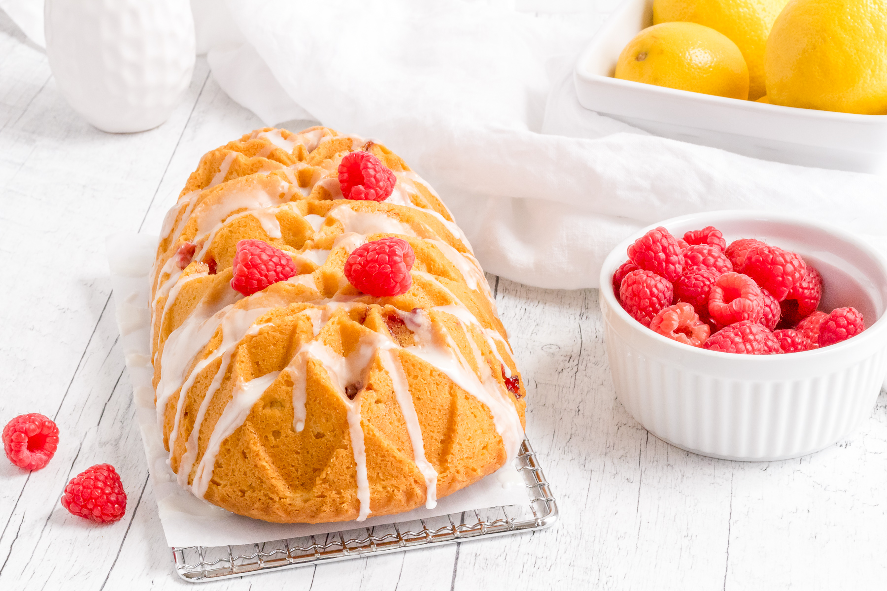lemon raspberry loaf with berries and basket of lemons. 