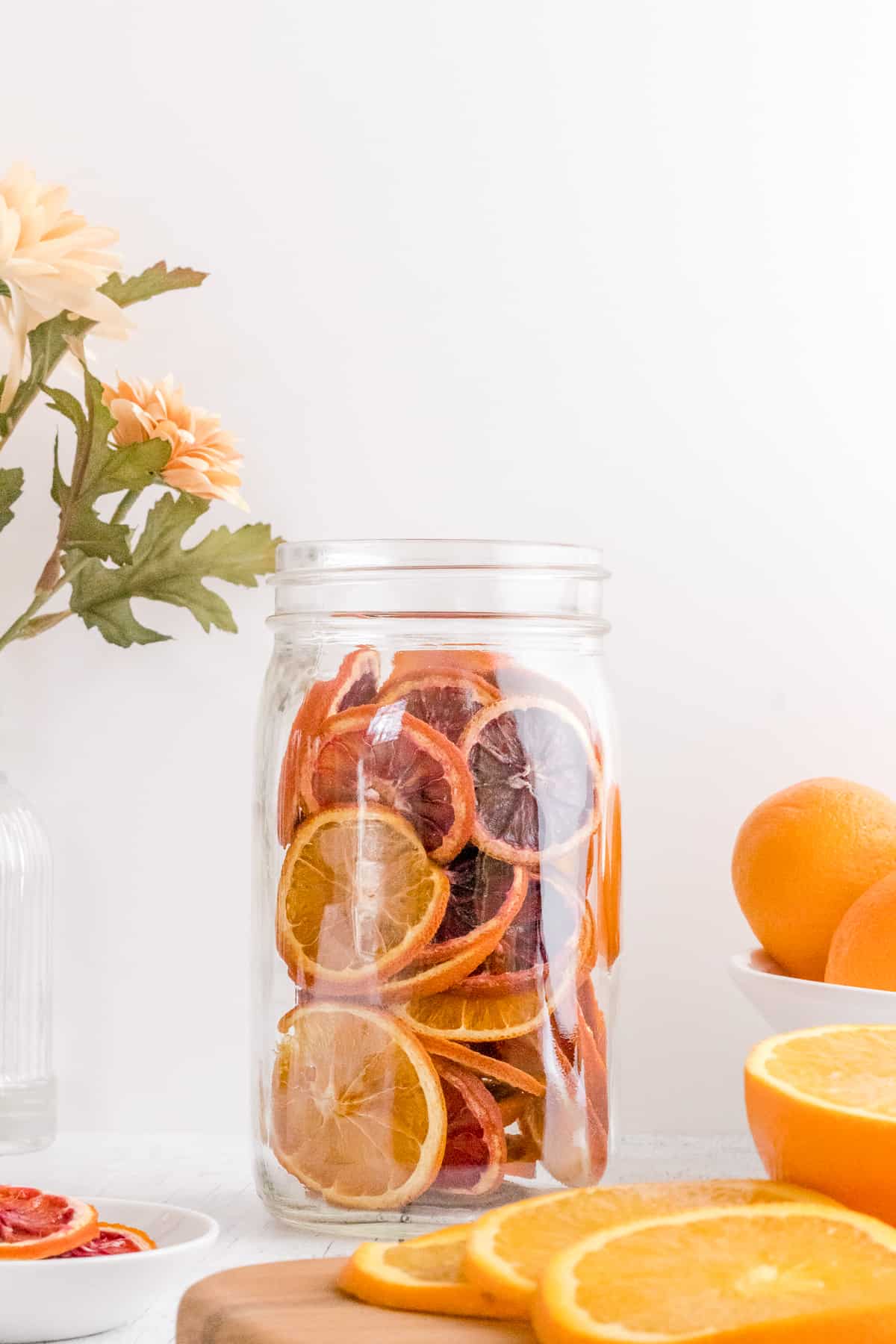 dehydrated orange slices in mason jar with sliced oranges.