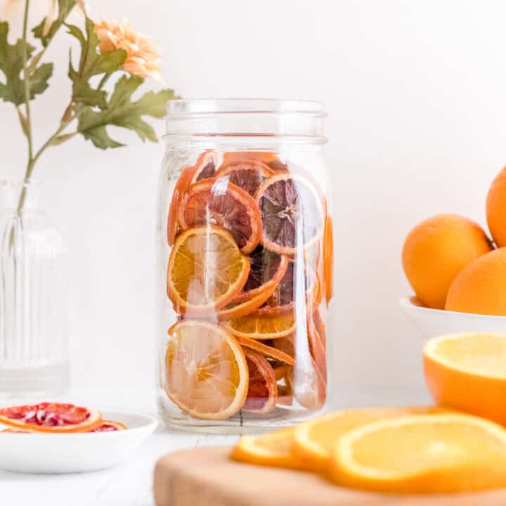 dehydrated orange slices with sliced oranges and vase of flowers.