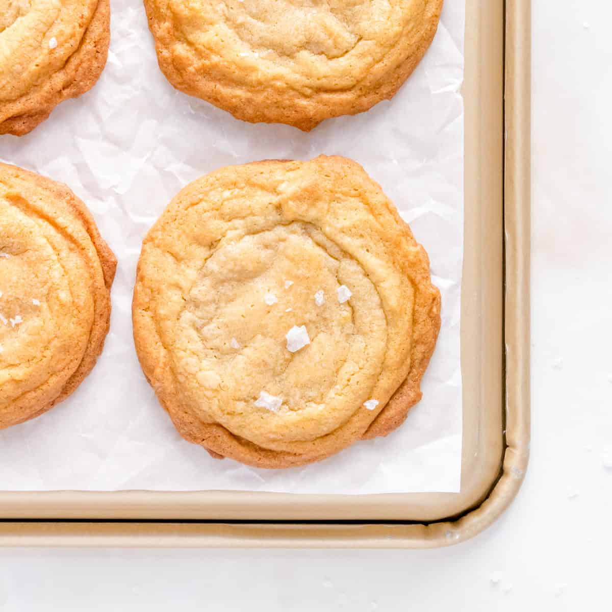 chocolate chipless cookie on gild sheet pan sprinkled with sea salt.
