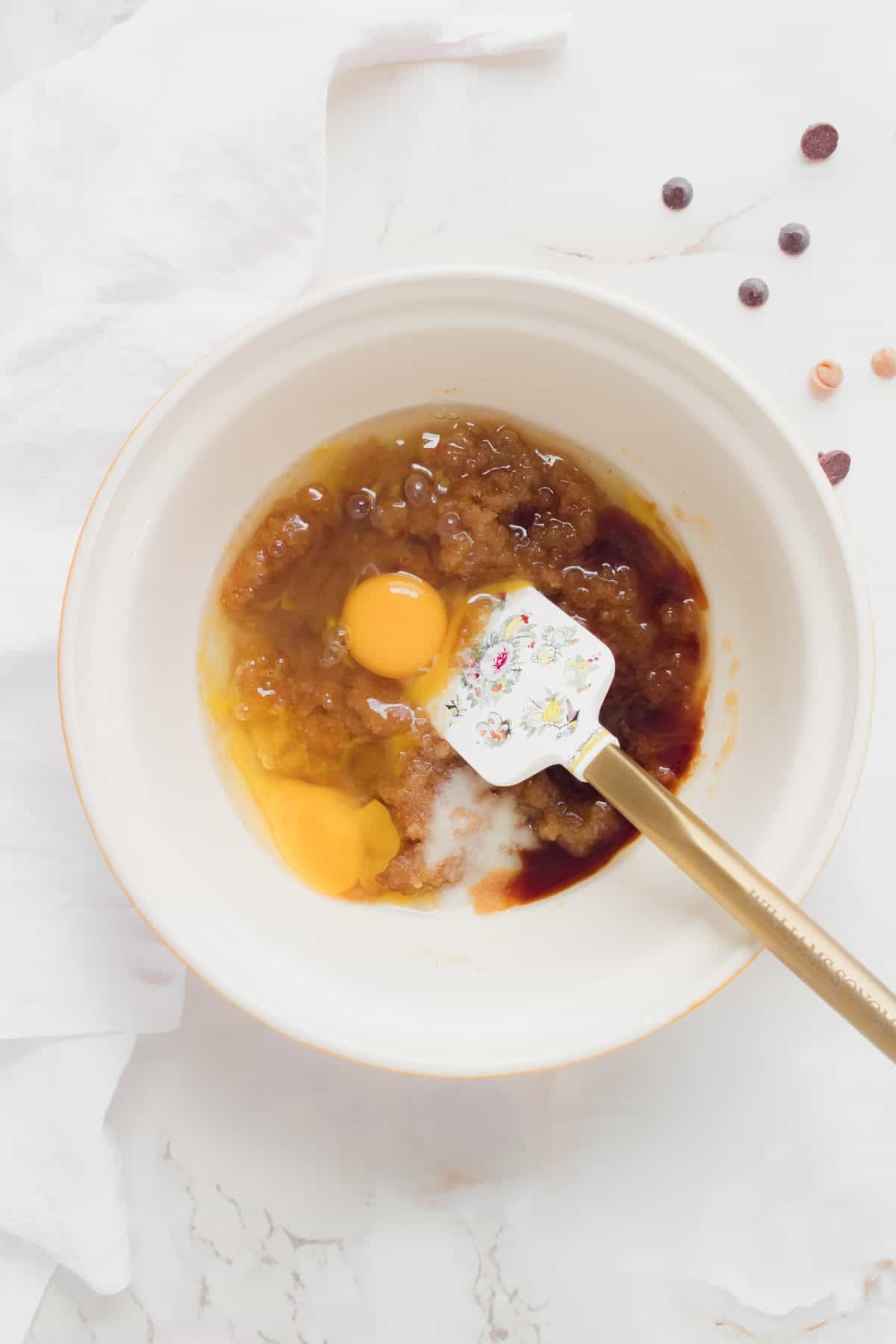 eggs and vanilla mixed with butter and sugar in ceramic mixing bowl.