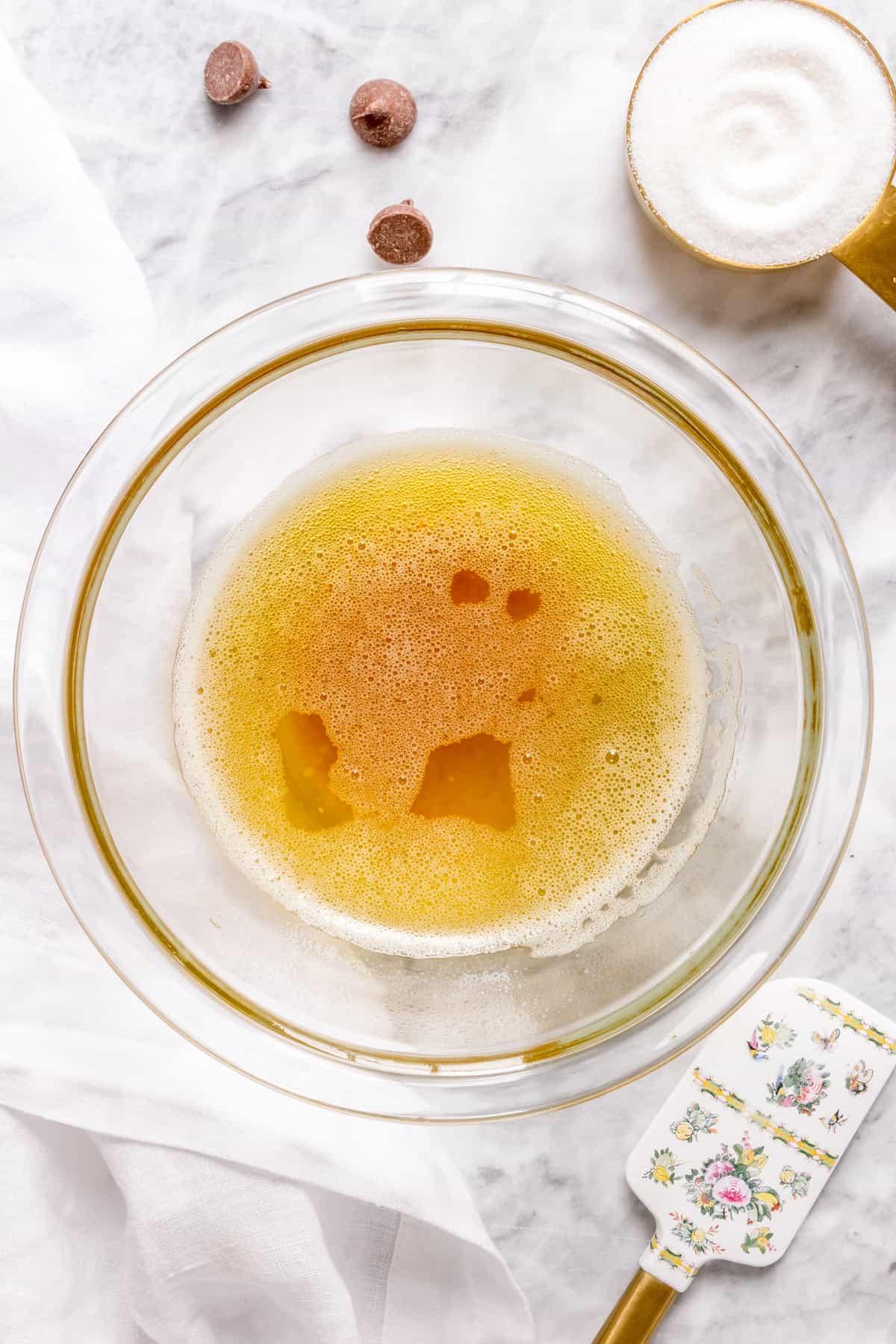 glass bowl of brown butter on marble counter with white napkin.