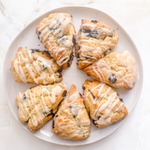 white round platter filled with blueberry scones on marble background.