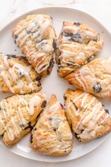 white round platter filled with blueberry scones on marble background.