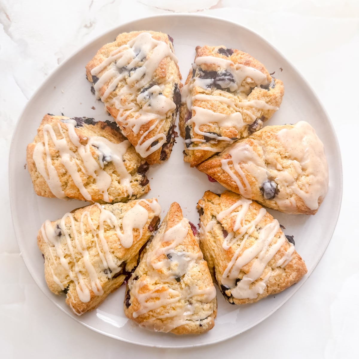 white round platter filled with blueberry scones on marble background.