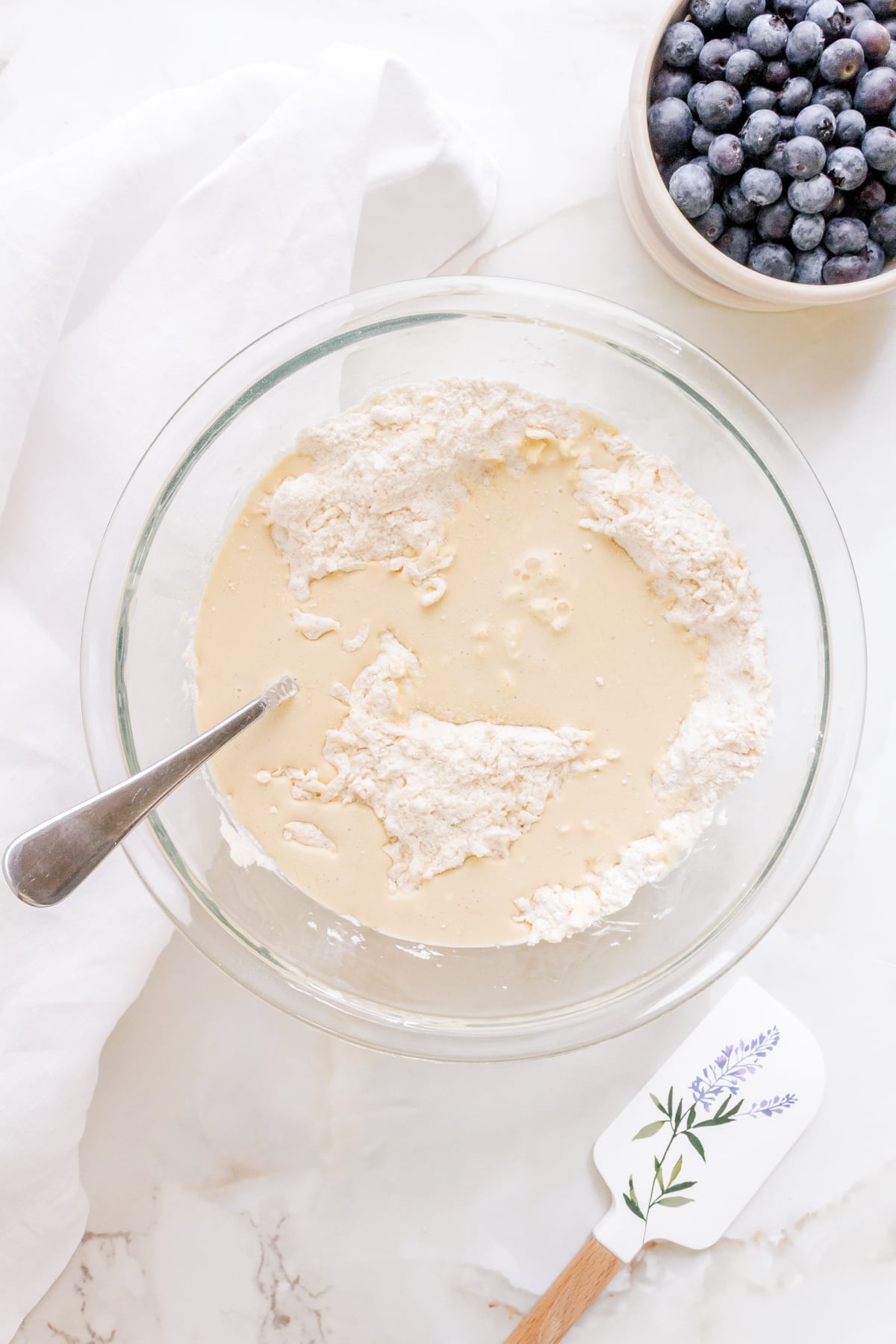 adding liquid ingredients to blueberry scones dough.