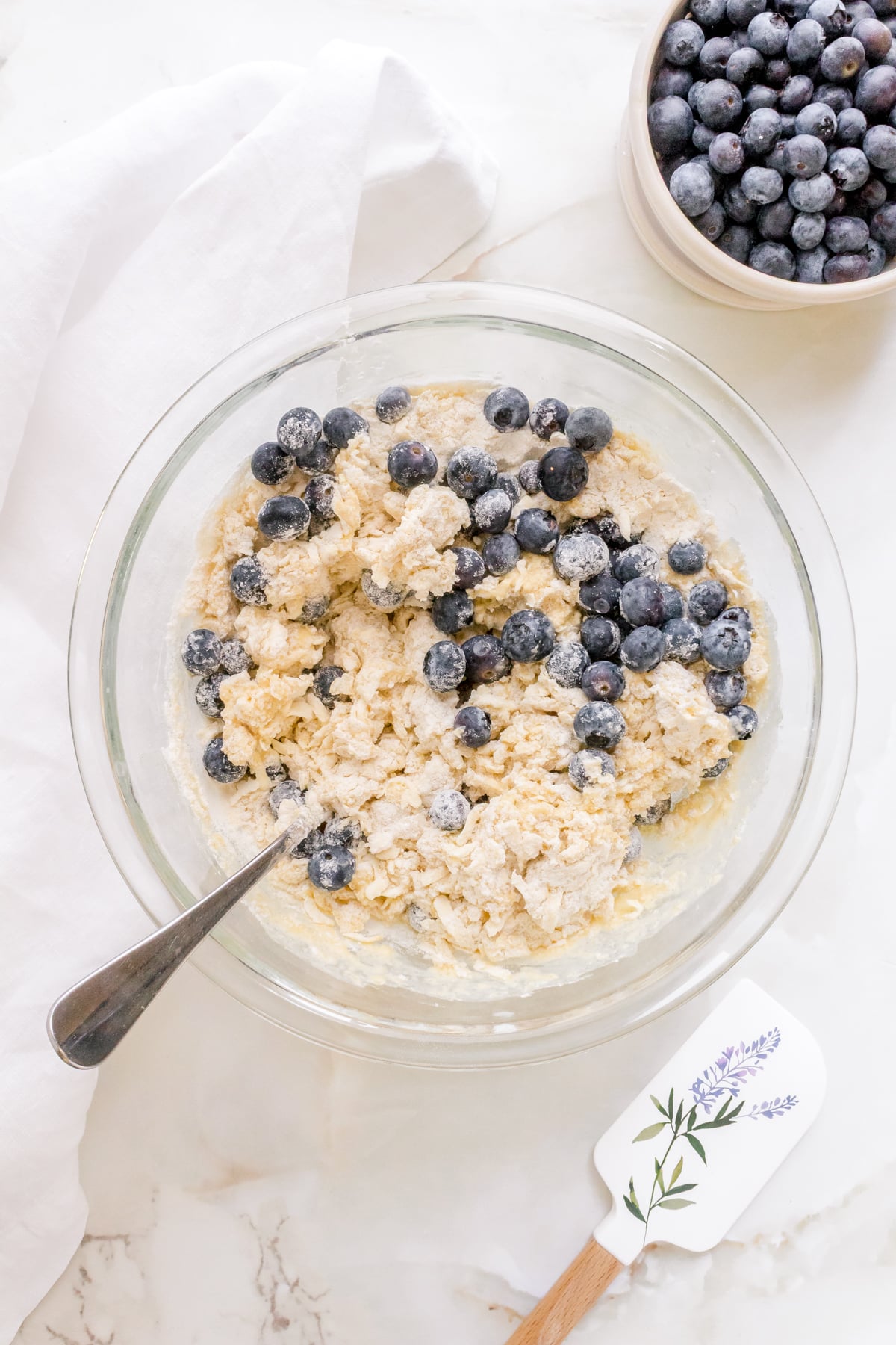 dough for blueberry scones in glass mixing bowl with a fork.