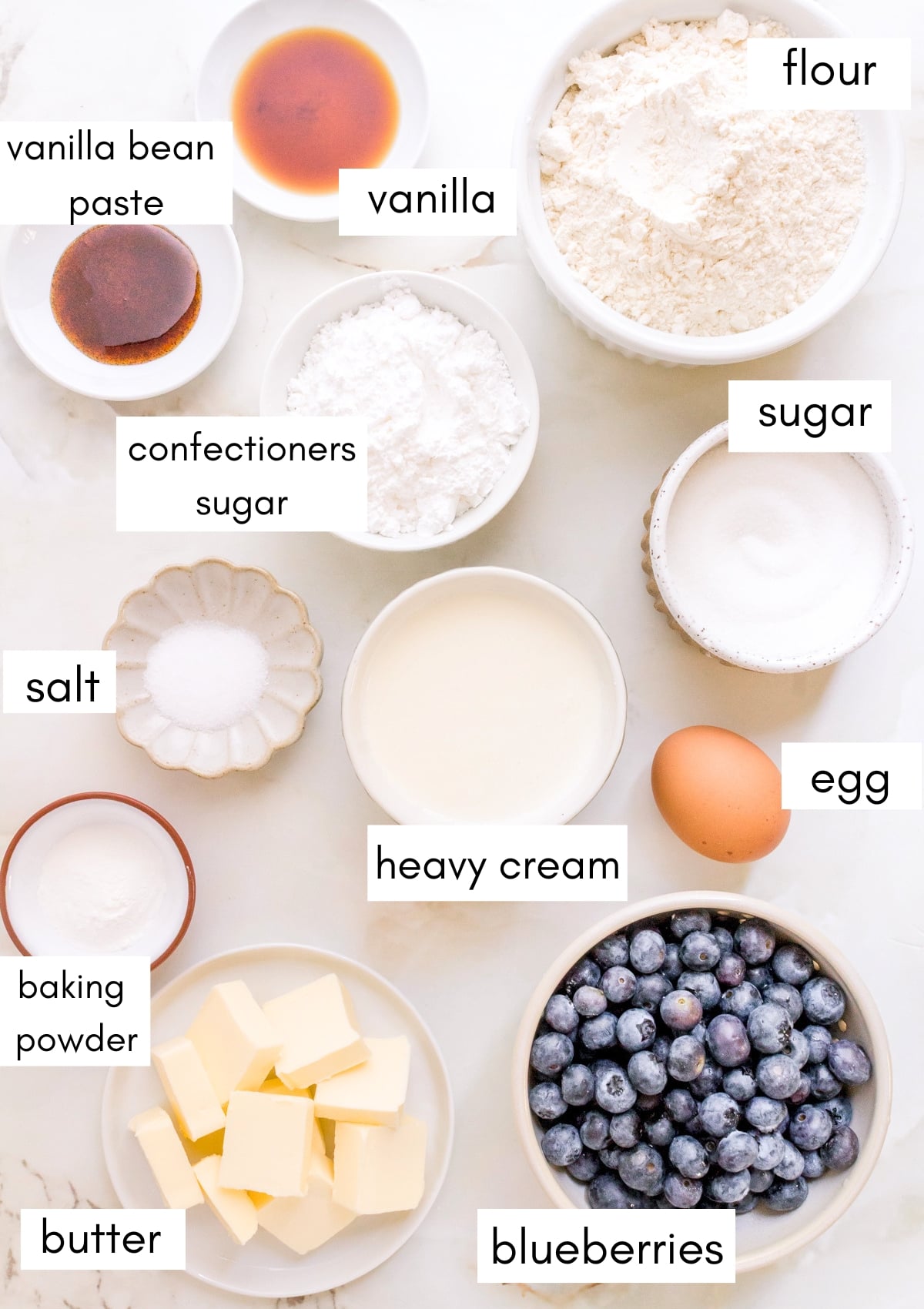 labeled ingredients for blueberry scones on marble counter.