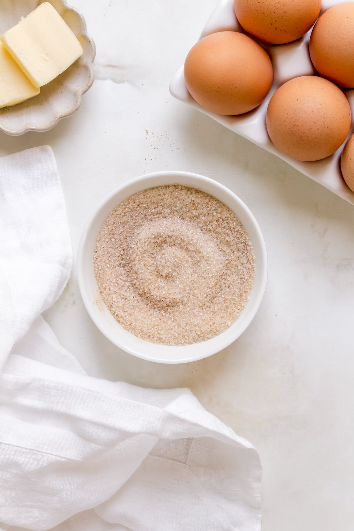 white bowl of cinnamon and sugar with butter and eggs. 