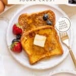 brioche French toast on white plate with gold fork, berries and maple syrup.