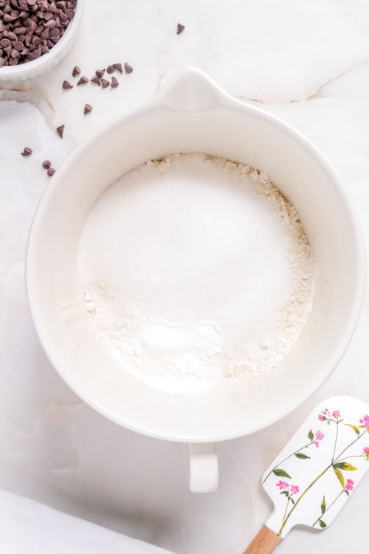 Flour, sugar, baking powder, and salt whisked together in a large white bowl.