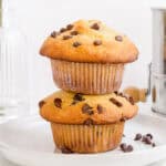 stack of chocolate chip banana muffins on white plate with mini chocolate chips.