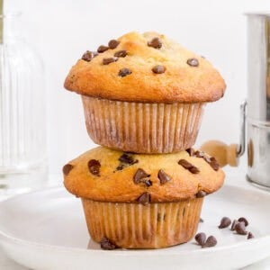 stack of chocolate chip banana muffins on white plate with mini chocolate chips.