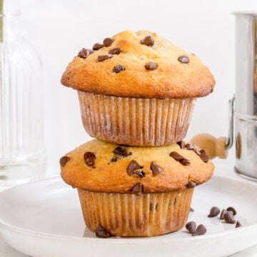 stack of chocolate chip banana muffins on white plate with mini chocolate chips.