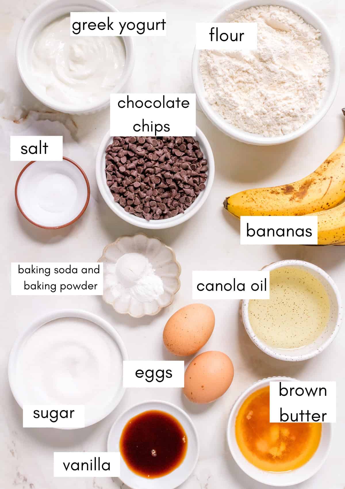 labeled ingredients for chocolate chip banana muffins on marble counter.