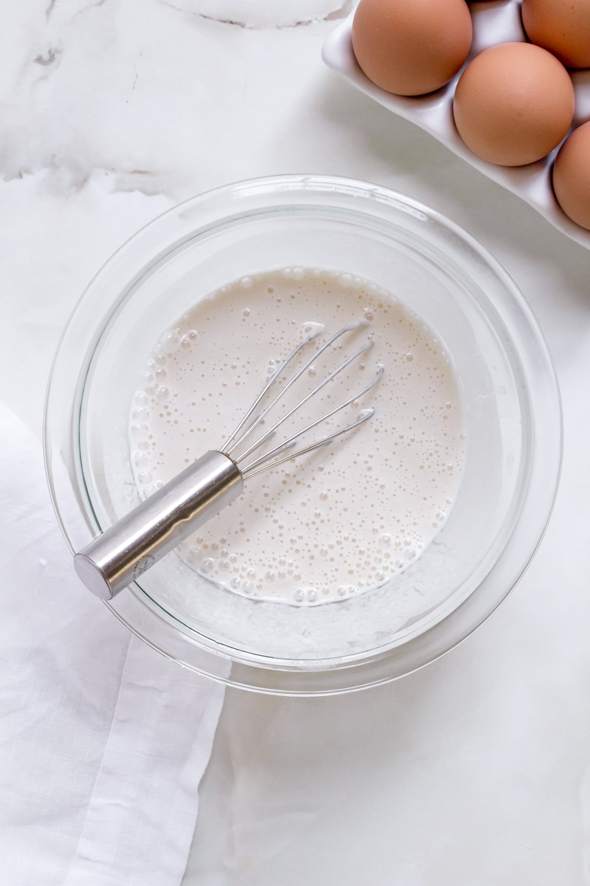 a small glass bowl of sourdough discard and water whisked in a mixing bowl. 