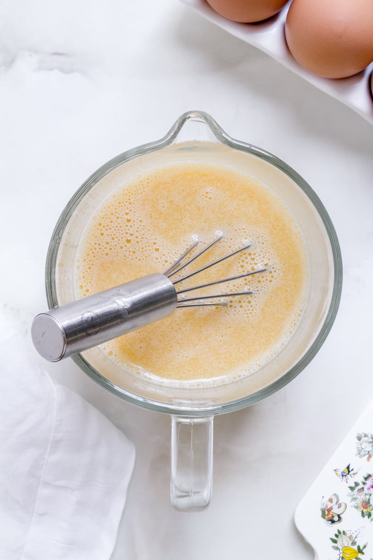 liquid ingredients for discard pancakes in glass measuring cup with whisk.