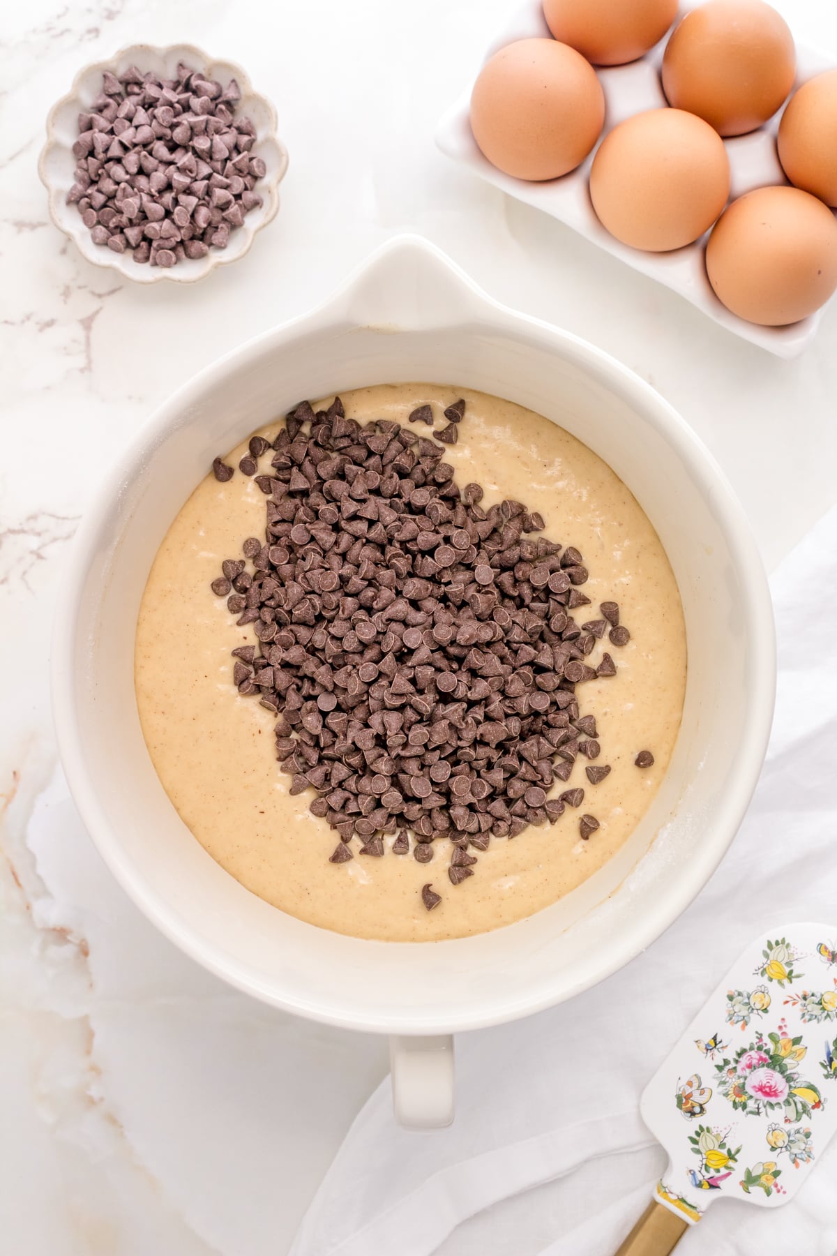 adding chocolate chips to pancake batter in white mixing bowl.