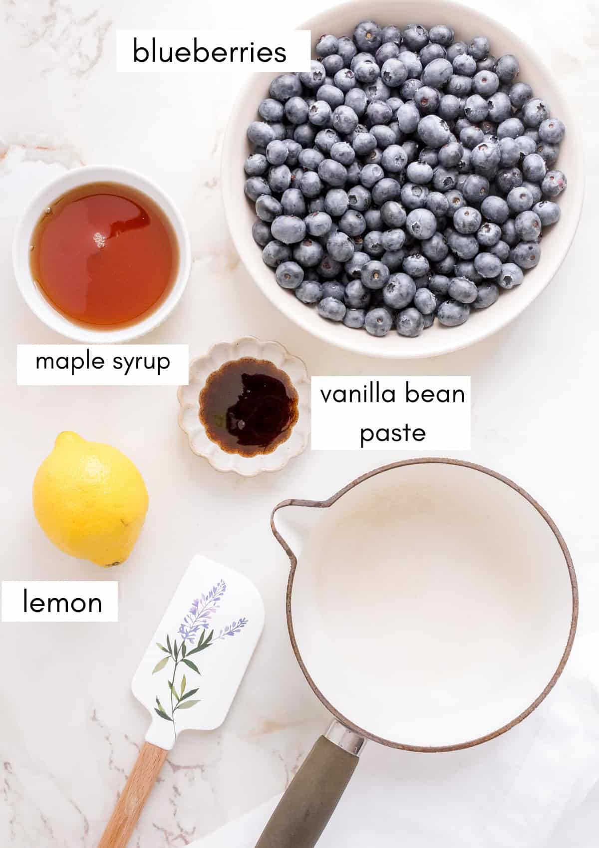 labeled ingredients for blueberry compote on white marble.