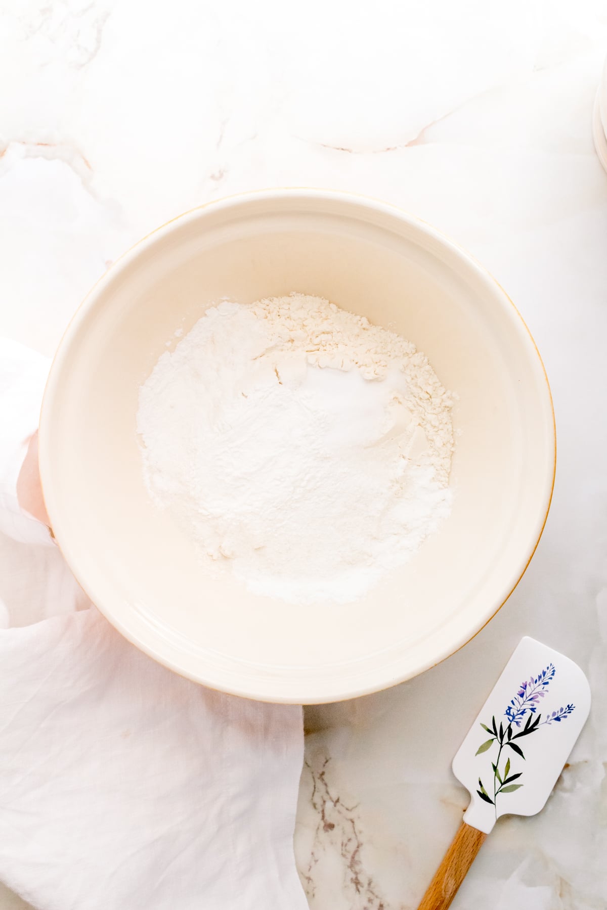 dry ingredients for discard waffles in large mixing bowl with flowered spatula.