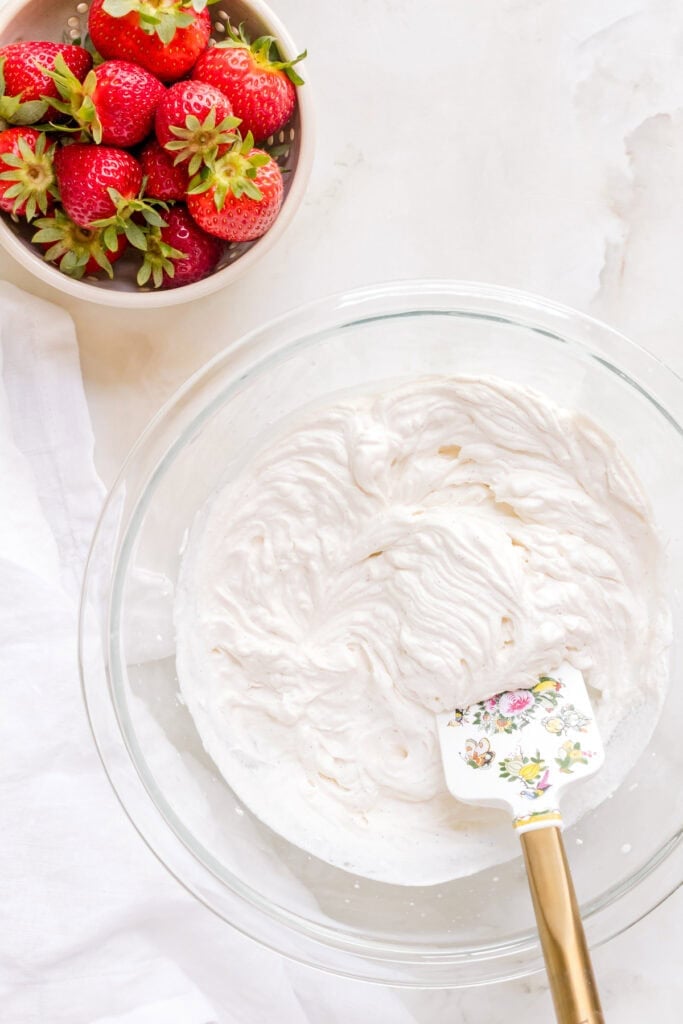 mixing whipped cream in glass mixing bowl.