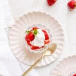 homemade whipped cream with strawberries in glass dish with a gold spoon.